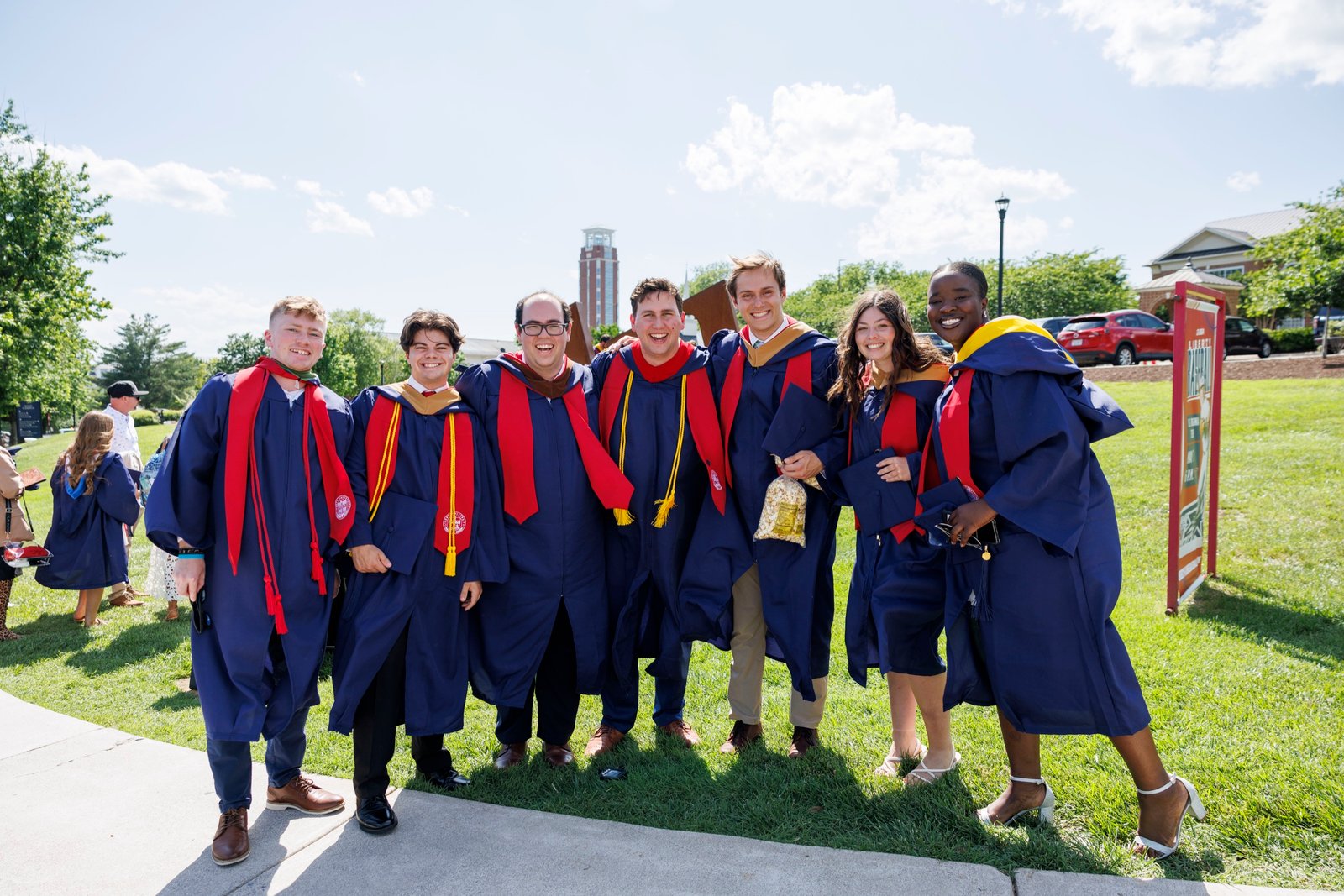 Two graduates celebrate together outdoors.