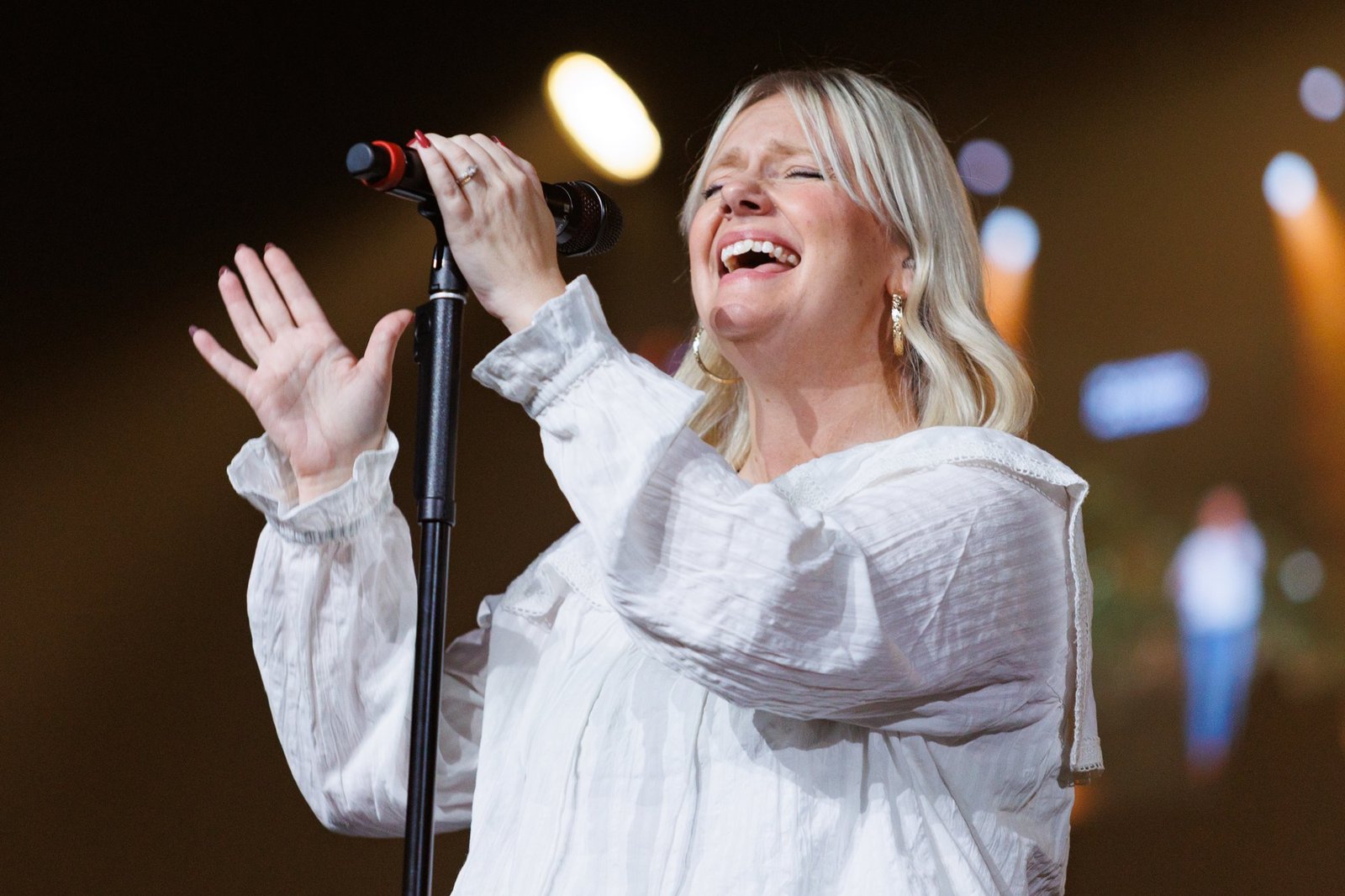 A singer leads worship under warm stage lights
