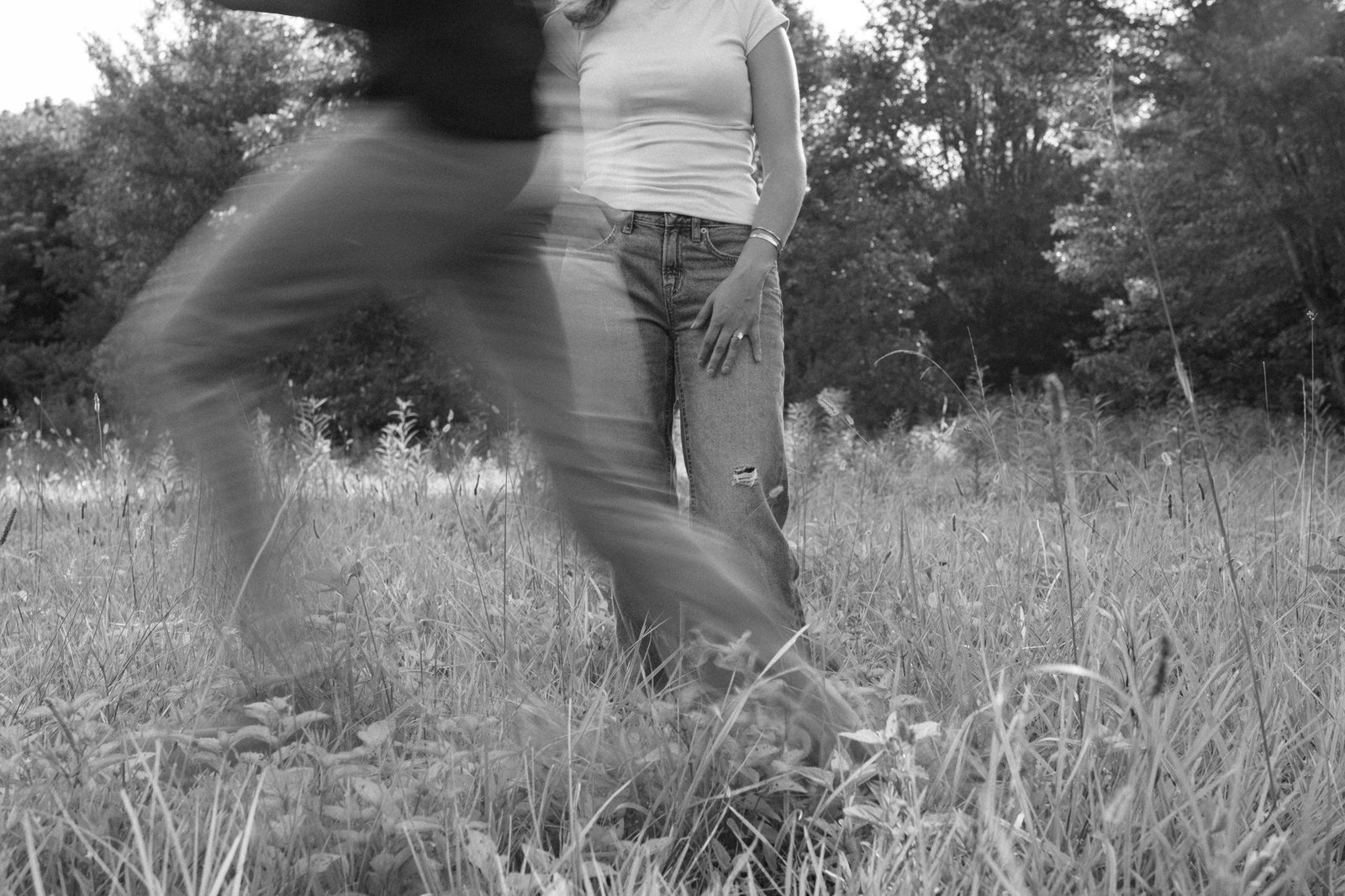 A couple moves through a field in a black-and-white photograph