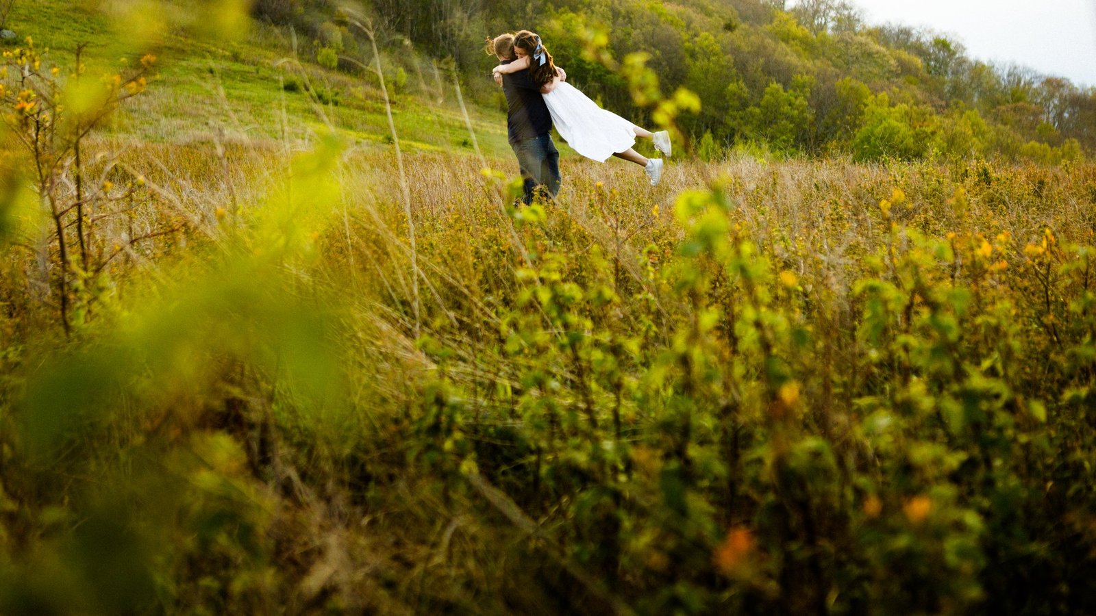 A couple embraces in a meadow