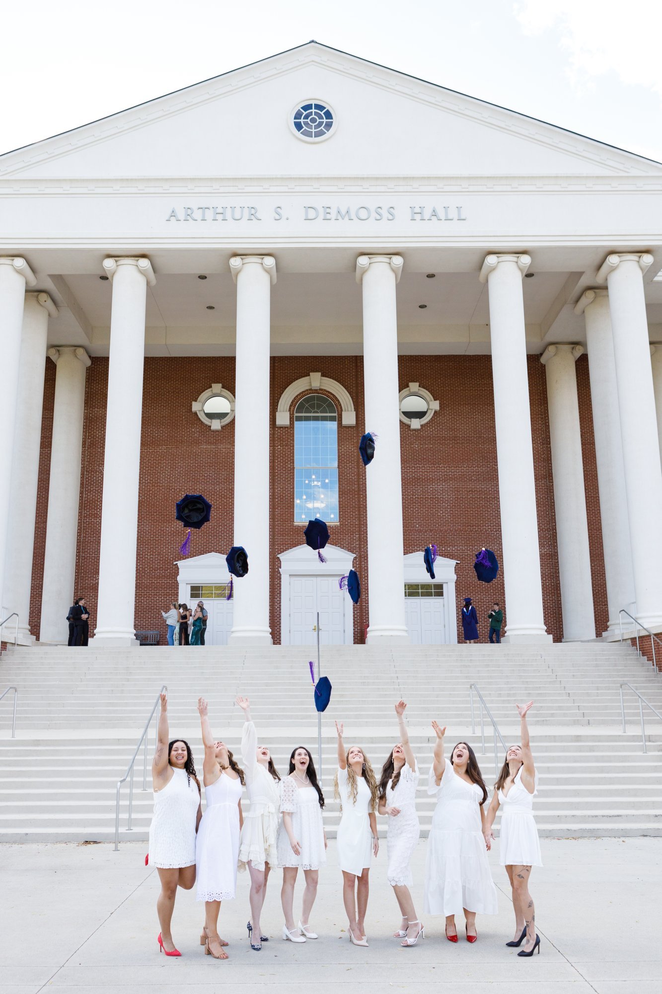 Graduates toss their caps in front of a campus building