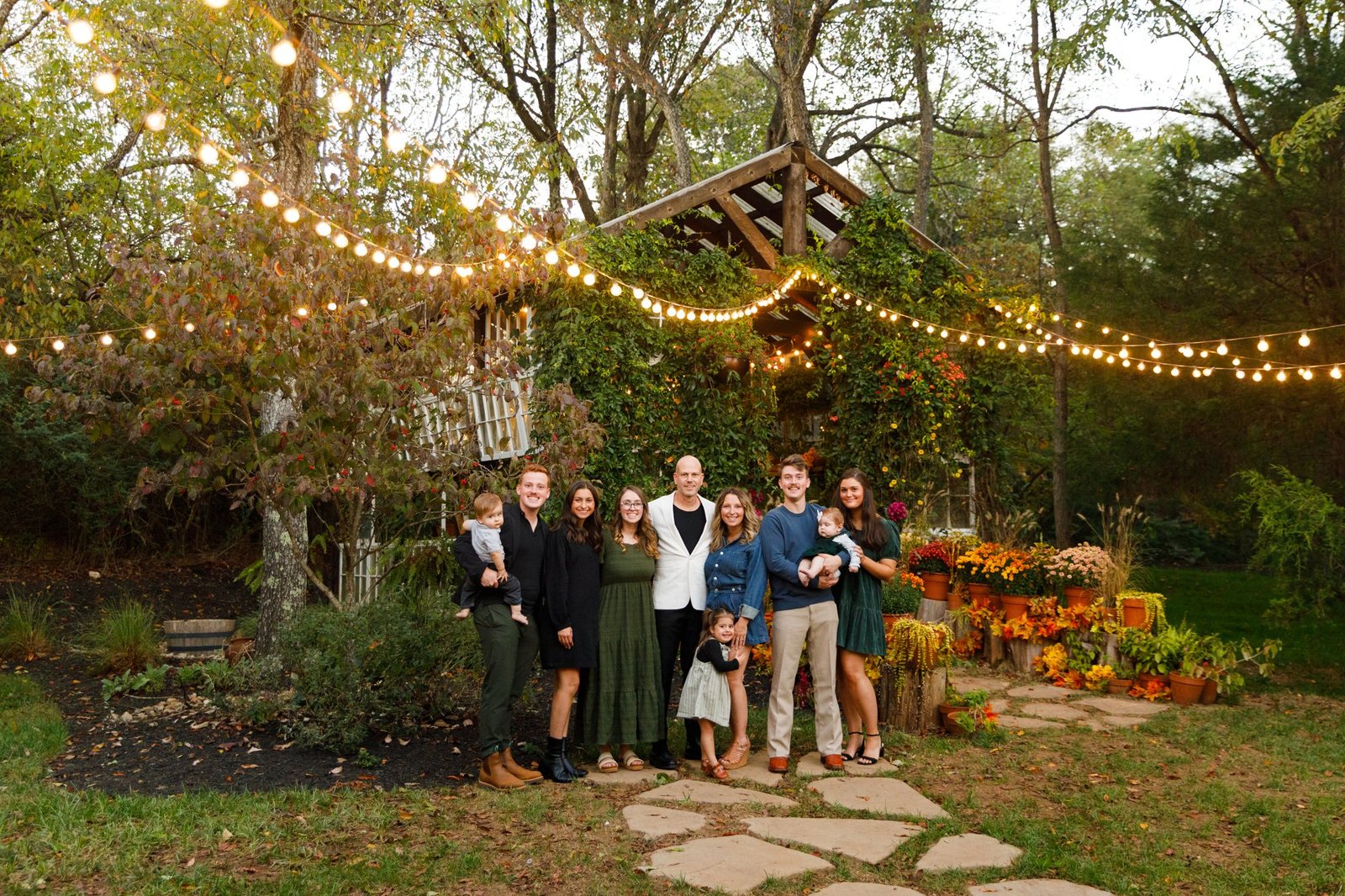 A family gathers beneath string lights in a garden