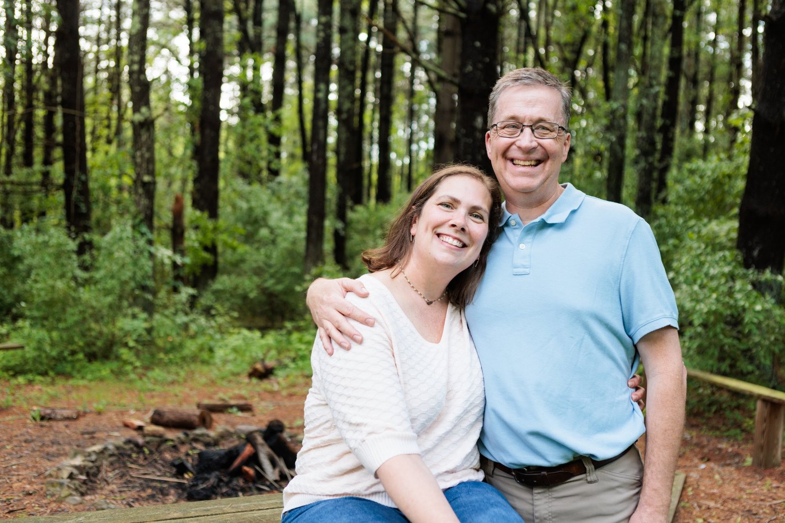 A couple smiles together in the woods