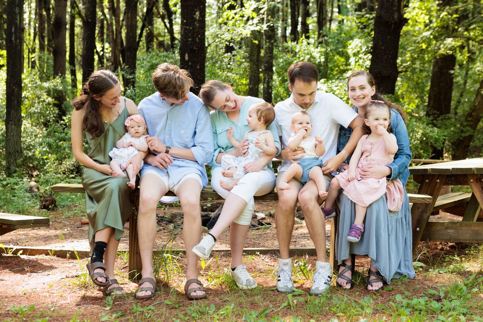 A family shares a candid moment on a bench in the woods