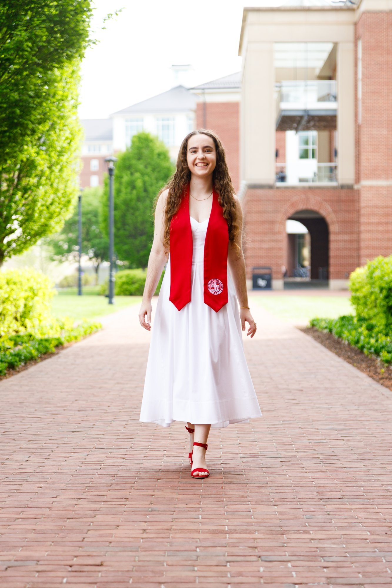A graduate walks along a brick campus path