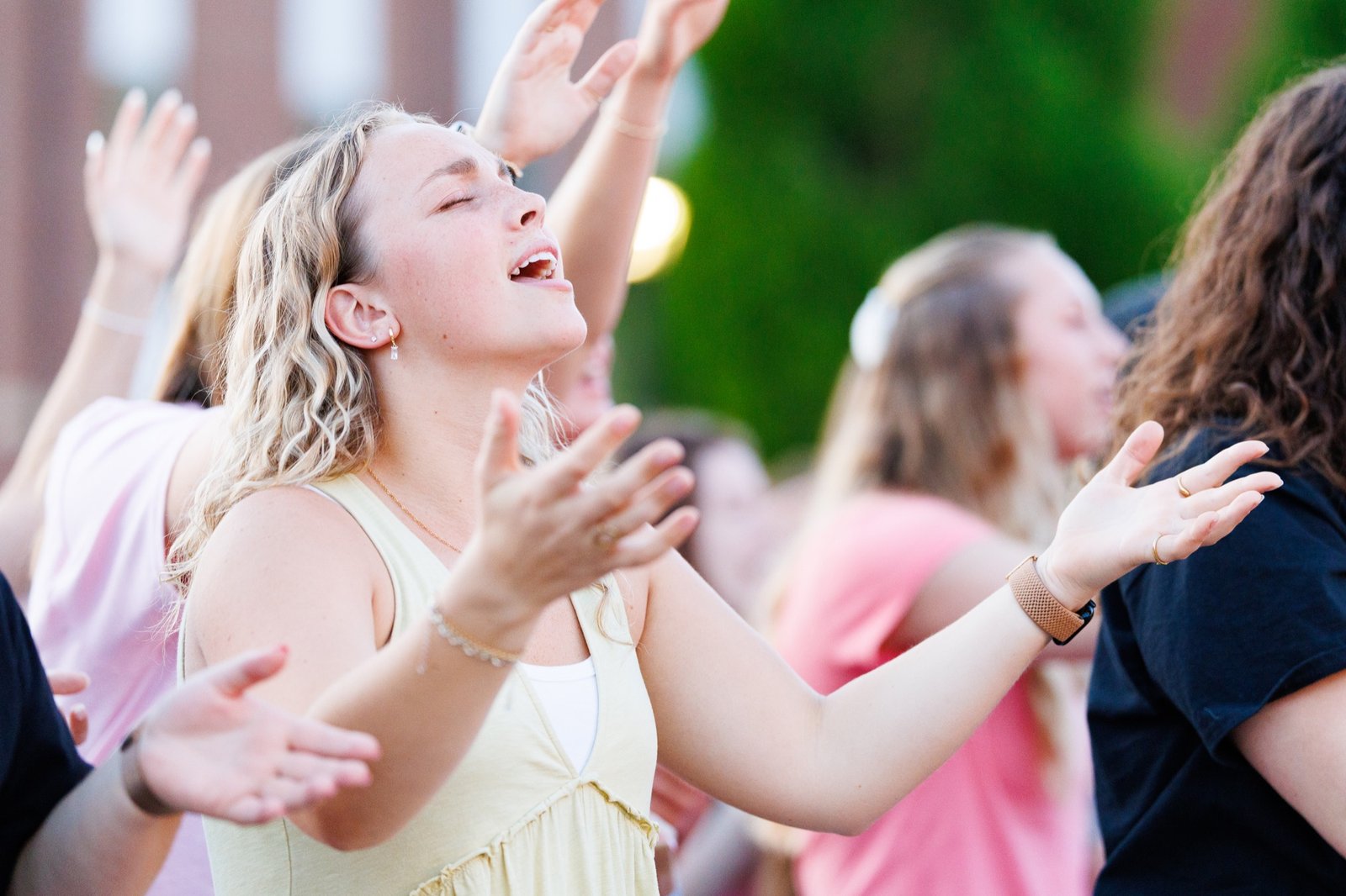 Students worship with raised hands in the evening light