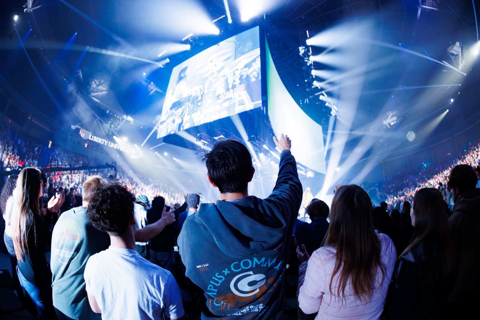 An audience watches a concert under blue stage lights