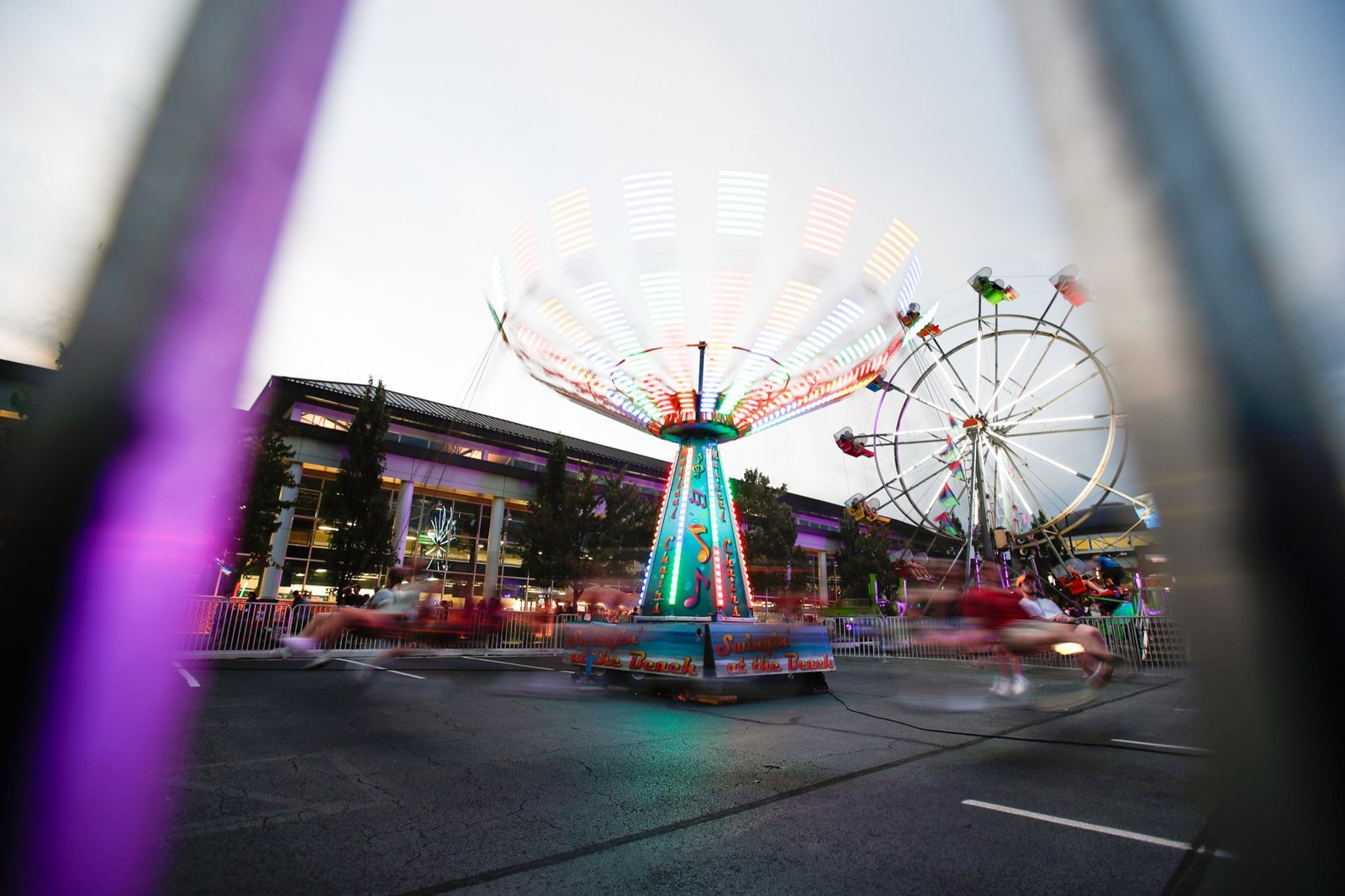 Carnival rides at Block Party, framed through a foreground structure