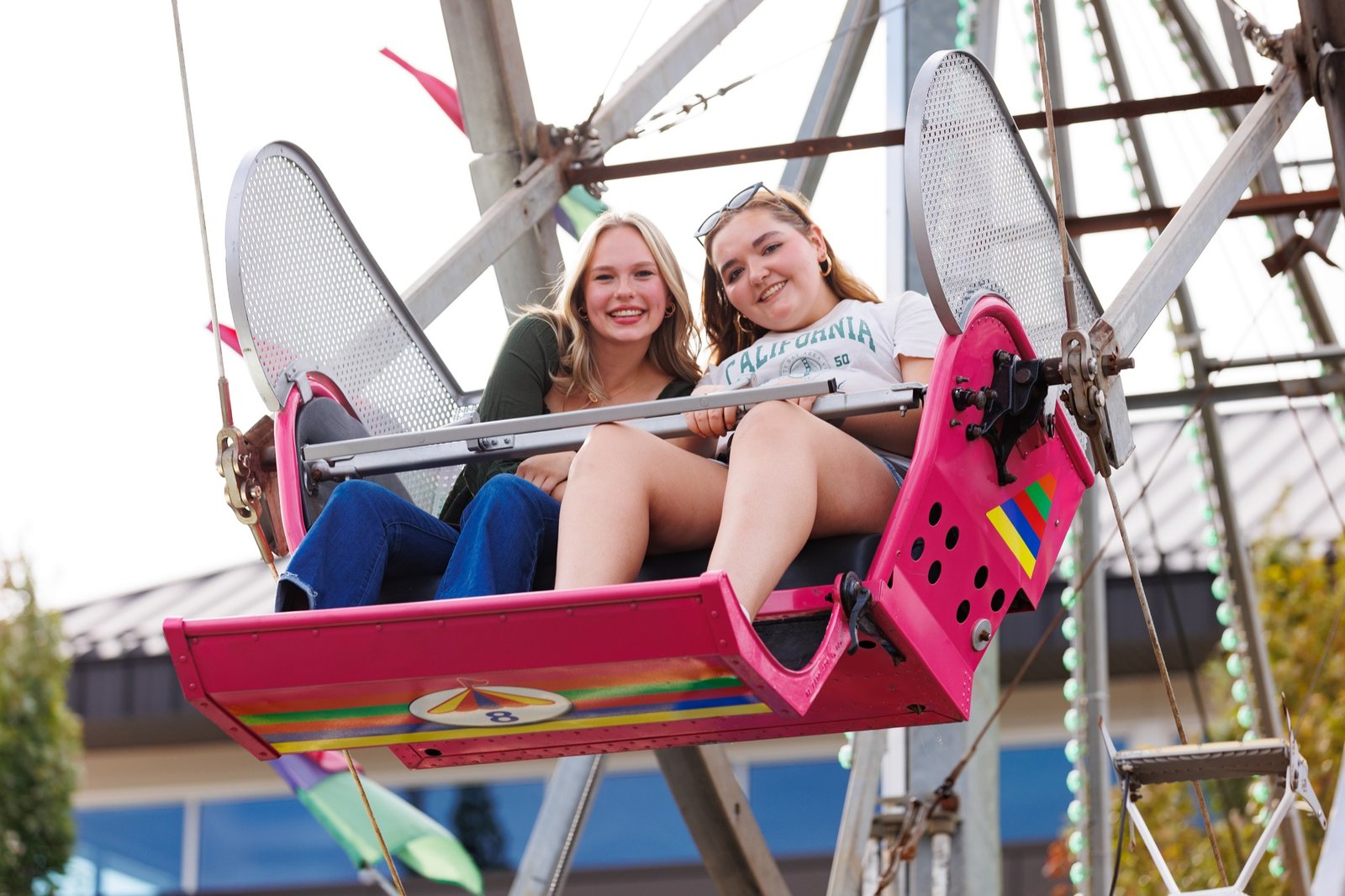 Two students ride a brightly colored Ferris wheel carriage