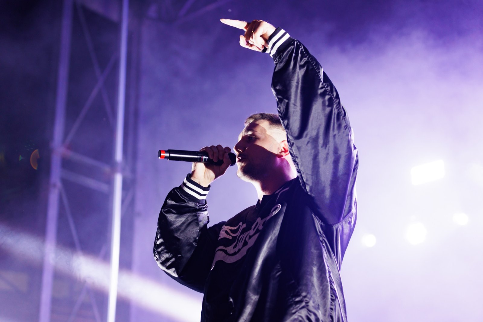 A singer raises his arm under purple Block Party stage lights