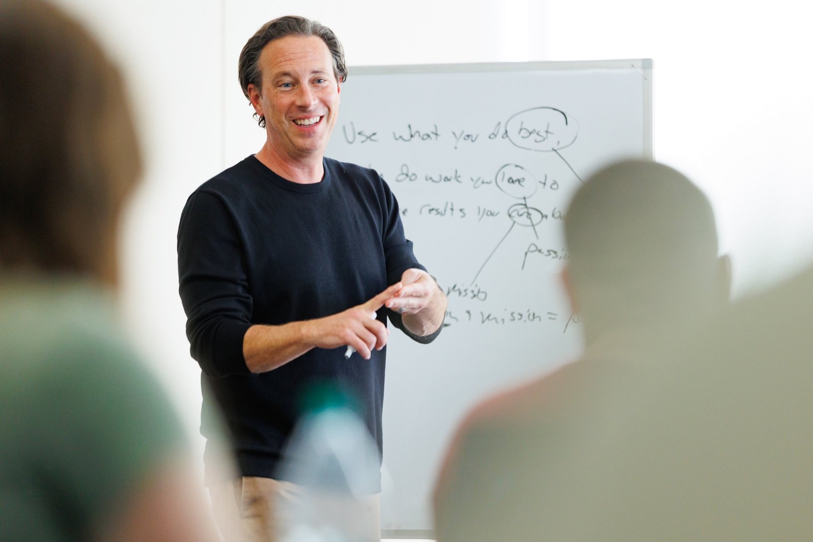 A speaker smiles beside a classroom whiteboard