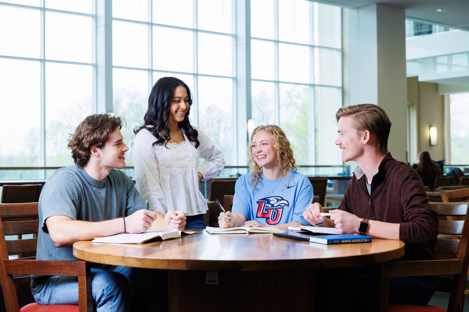 Students gather around a table in a sunlit campus study space