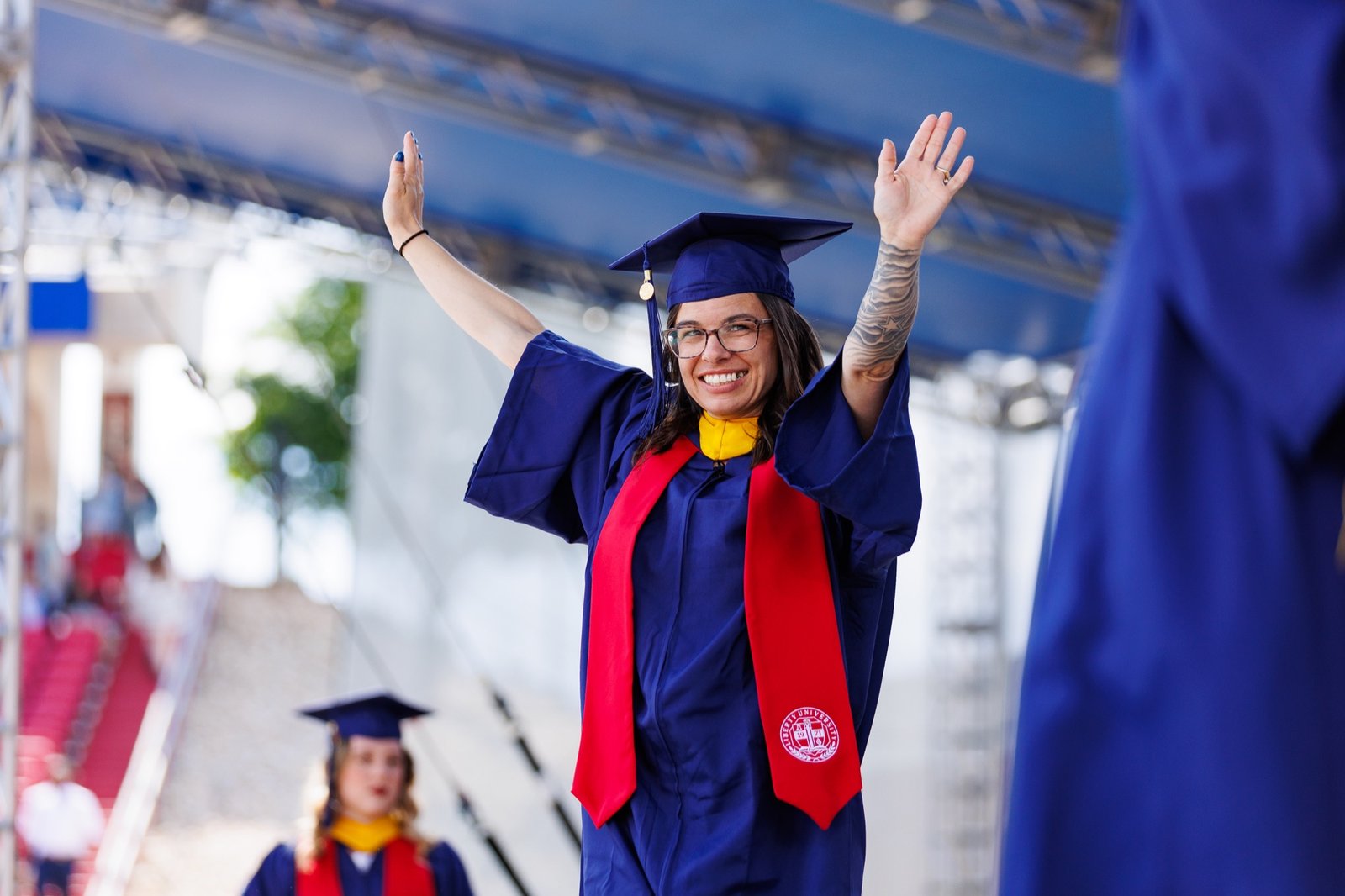 A graduate raises both arms during commencement