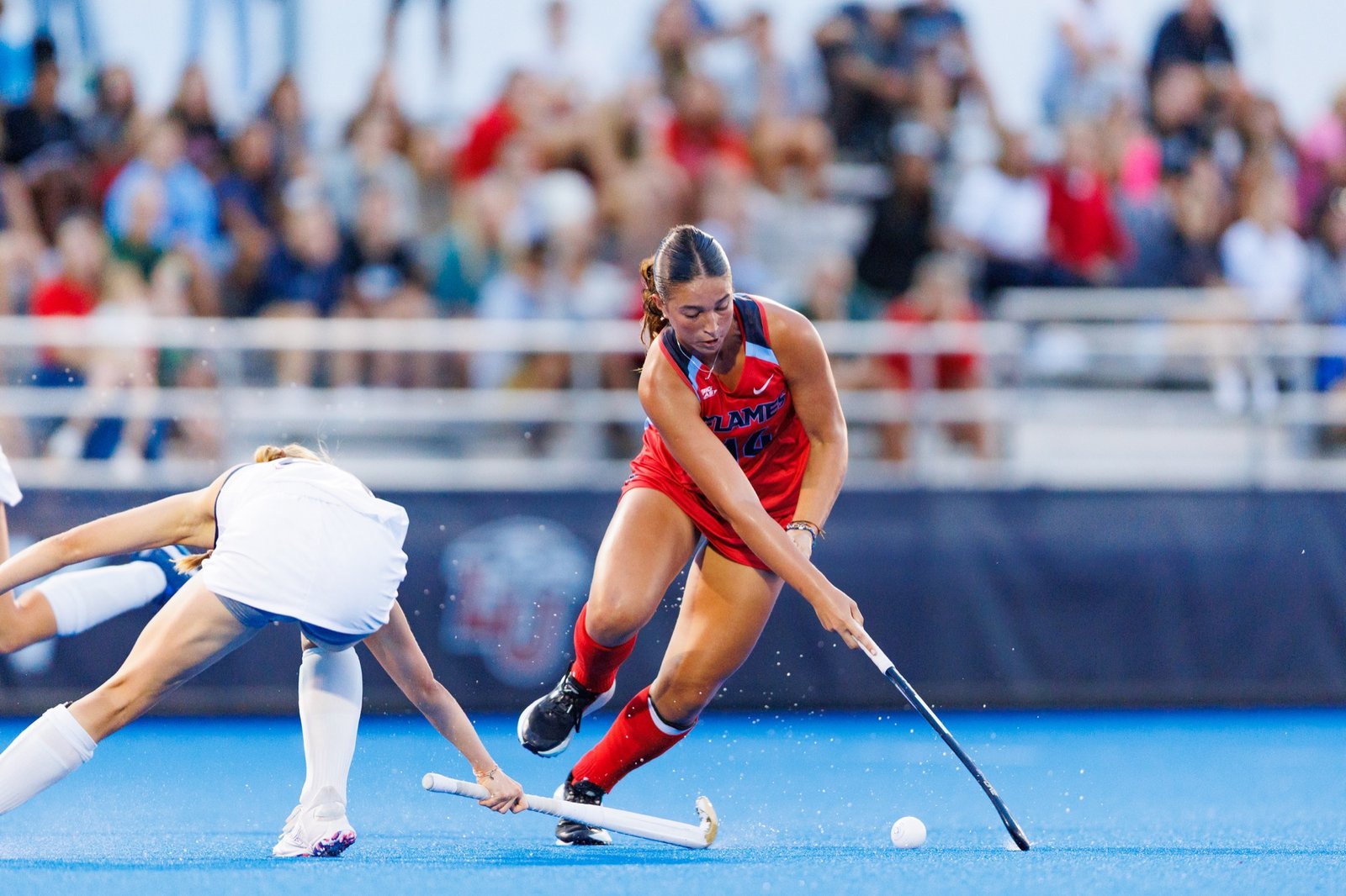A field hockey player challenges an opponent for the ball