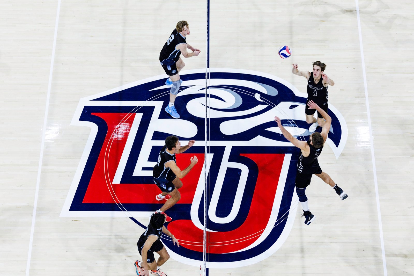 Basketball players cross the Liberty center-court logo