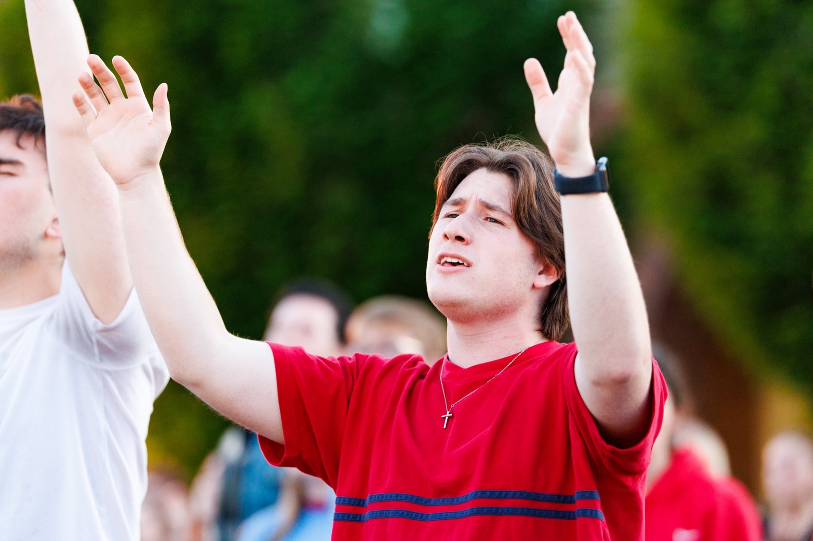 A student raises his hands during outdoor worship