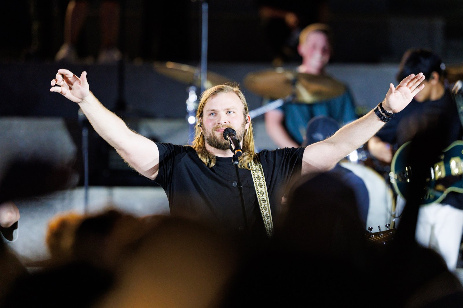 A worship leader opens his arms toward the audience